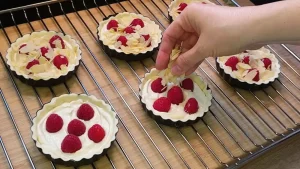 Gehobelte Mandeln werden vor dem Backen über die Himbeeren und die Creme gestreut.