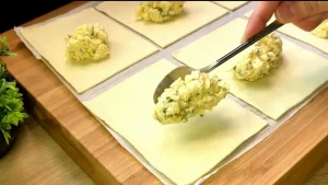 Eine Mischung aus Frischkäse, geriebenem Käse und Schnittlauch wird auf die untere Hälfte der Teigstücke gegeben