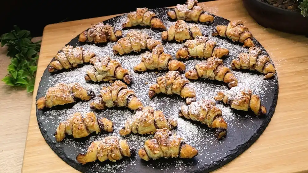 Goldbraun gebackene Mini-Blätterteigcroissants mit Kakaofüllung und Haselnuss-Topping.