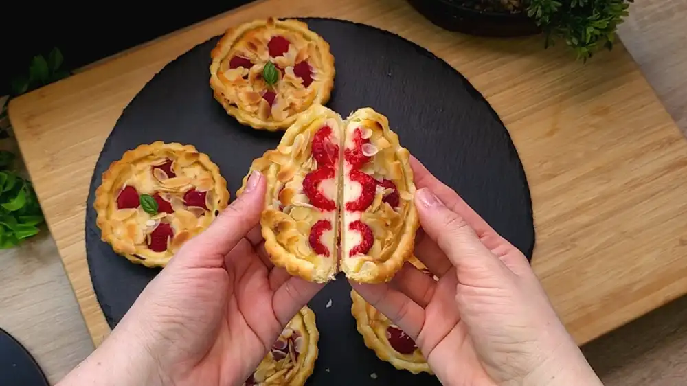 Eine Mini-Tarte wird leicht gebogen, um die Knusprigkeit des Blätterteigs zu zeigen.