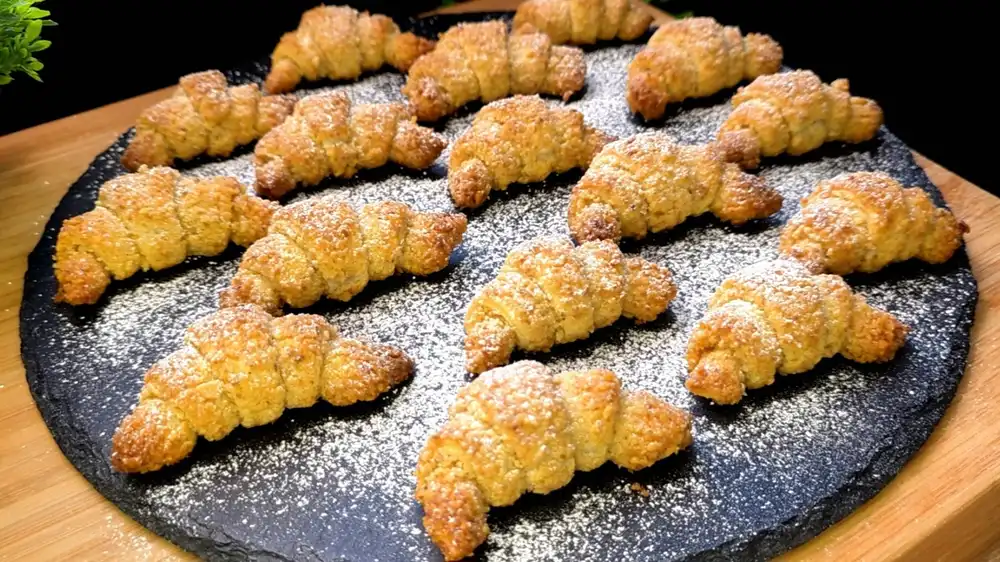 Goldbraun gebackene Mini-Walnuss-Croissants mit Puderzucker bestäubt.