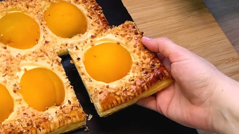 Detailansicht eines Kuchenstücks mit cremiger Quarkfüllung und Pfirsichhälften