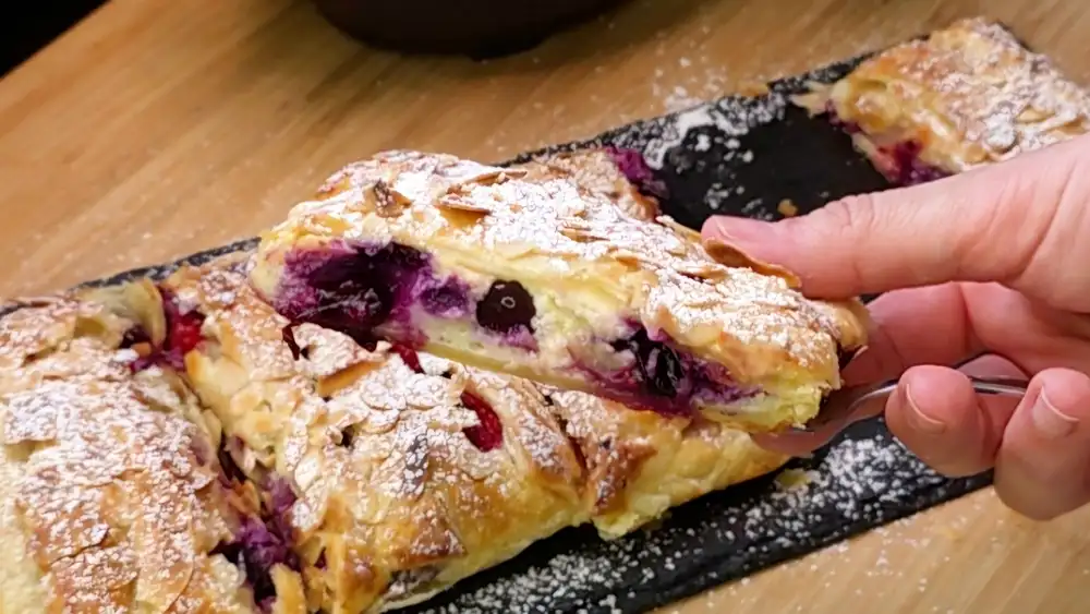 Detailansicht des Anschnitts zeigt die cremige Quarkfüllung mit Heidelbeeren und Himbeeren.