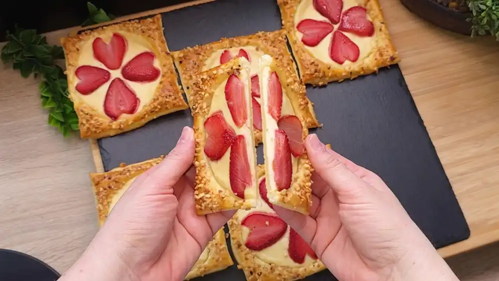 Ein halbierter Mini-Kuchen zeigt die cremige Quarkfüllung unter den Erdbeeren.