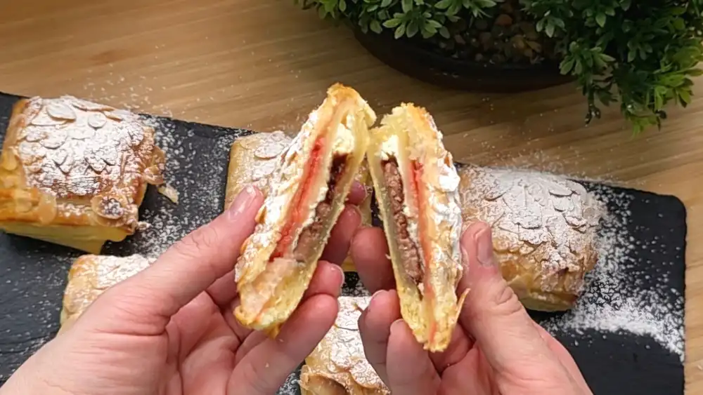 Detailansicht eines aufgeschnittenen Blätterteig-Kissens mit geschmolzener Schokolade und Erdbeeren.