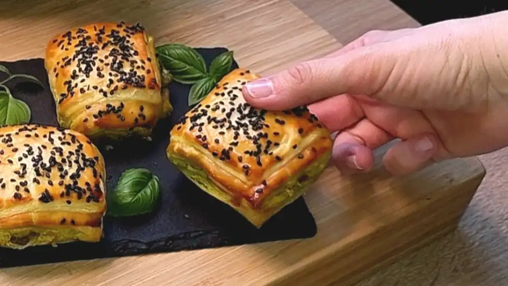 Detailansicht einer knusprigen Teigtasche mit geschmolzenem Käse und Pesto