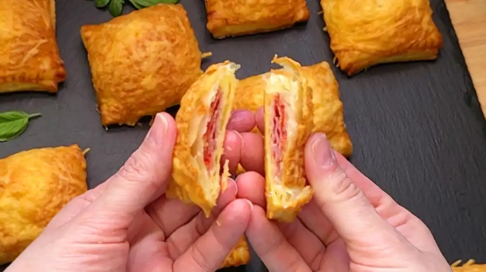 Detailansicht eines Häppchens zeigt die Salami, Tomatenscheiben und geschmolzenen Käse.