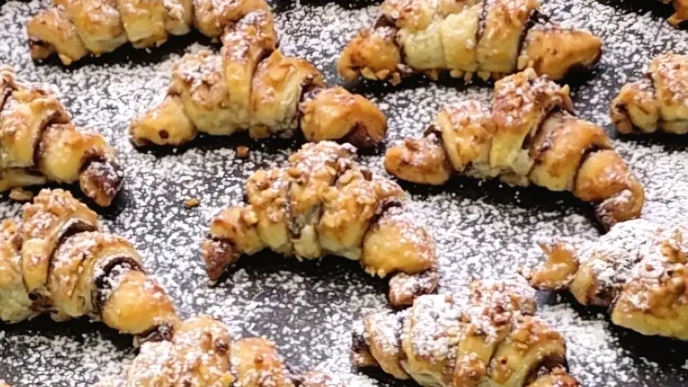 Detailansicht eines Mini-Croissants zeigt die blättrigen Schichten und die gehackten Haselnüsse.