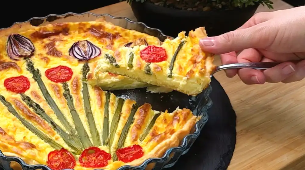 Detailansicht eines frisch abgeschnittenen Stücks Spargel-Quiche mit saftiger Hollandaise-Füllung.