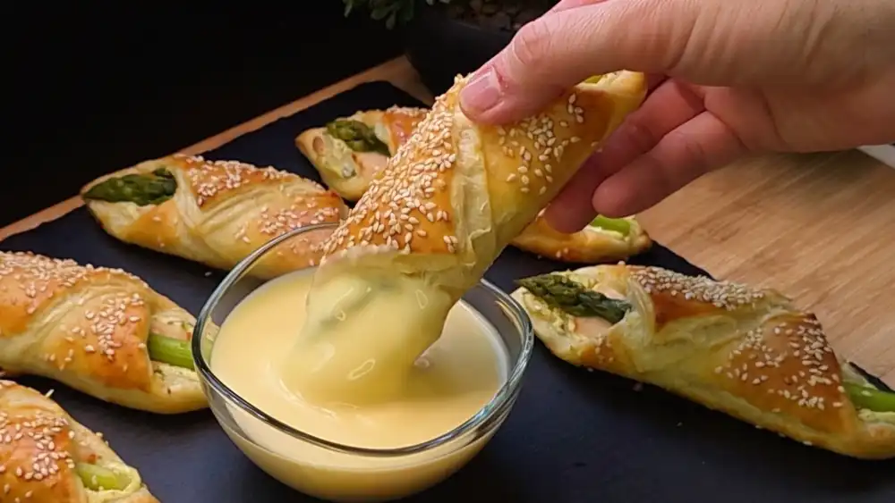 Detailansicht einer knusprigen Blätterteig-Tasche mit grünem Spargel und Sesam.