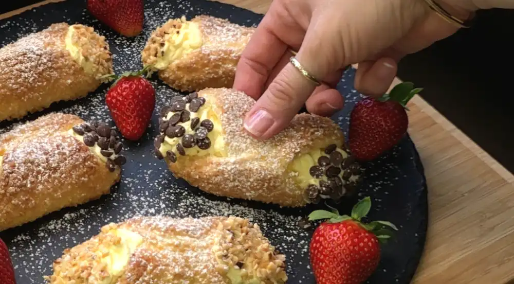 Detailansicht einer gefüllten Rolle mit Schokotropfen und gehackten Haselnüssen an den Enden.