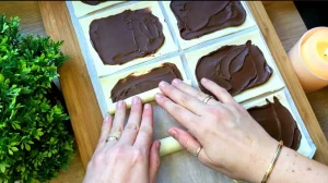 Eine Person streicht Nutella auf ein rechteckiges Stück Blätterteig.