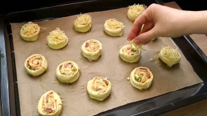 Die geschnittenen Teigschnecken liegen auf dem Blech und werden mit restlichem Käse bestreut.