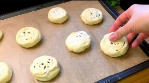 Ungebackene Blätterteigrollen liegen fertig mit Ei bestrichen auf dem Backblech