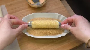 Die vorbereiteten Blätterteigrollen liegen aufgereiht auf einem Backblech mit Backpapier.