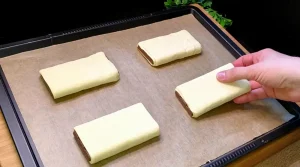 Die gerollten Schokotaschen liegen fertig bestrichen und mit Mandeln bestreut auf dem Backblech.