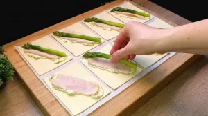 Grüner Spargel wird auf eine Scheibe Hähnchenbrust mit Kräuterfrischkäse gelegt.