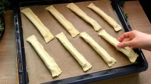Die vorbereiteten, mit Ei bestrichenen Spargelstangen liegen fertig auf dem Backblech.