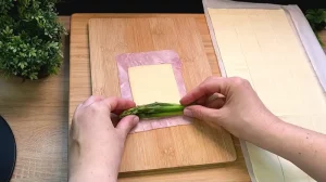 Grüner Spargel wird in eine Scheibe Käse und Prosciutto eingewickelt.