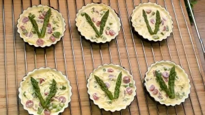 Die Ei-Käse-Salami-Mischung wird in die Teigformen gefüllt und mit Spargel dekoriert.