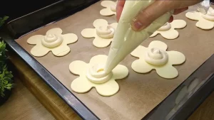 Die Vanille-Quark-Masse wird punktgenau in die Mitte der ausgestochenen Teigblumen gesetzt.
