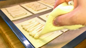 Die vorbereitete Vanille-Quark-Creme wird mittig auf die Blätterteig-Quadrate gegeben.