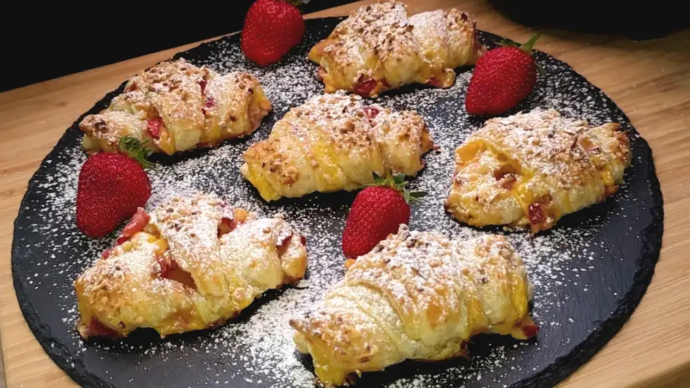 Goldbraun gebackene Blätterteig-Croissants gefüllt mit Vanillepudding und Erdbeeren.