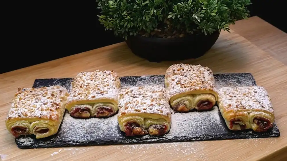 Goldbraun gebackene Blätterteig-Erdbeer-Schoko-Kissen mit Haselnuss-Topping und Puderzucker.