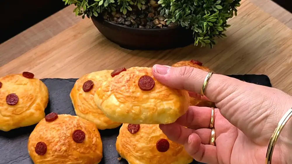 Detailansicht einer frisch gebackenen Käse-Tasche, bei der der geschmolzene Käse an den Seiten leicht herausbäckt und die Salami-Ringe perfekt kross geröstet sind.