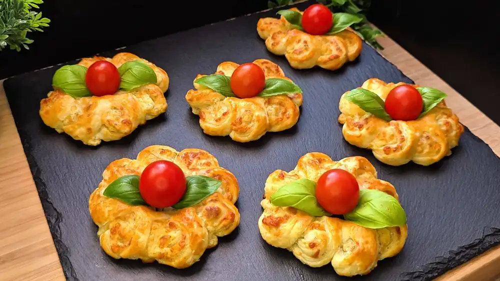 Goldbraun gebackene Käseblumen aus Blätterteig mit einer glänzenden Kruste und geschmolzenem Käsekern.