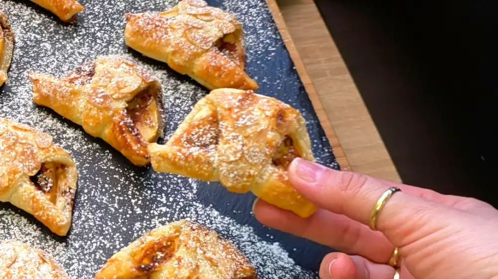 Detailansicht einer geöffneten Apfeltasche mit cremiger Frischkäsefüllung, Zimt-Zucker und saftigen Apfelscheiben.