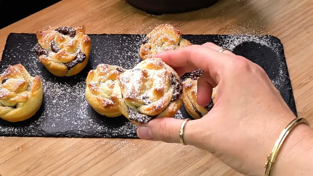 Detailansicht einer aufgeschnittenen Blätterteig-Nutella-Rose, die die krossen, blättrigen Schichten und den warmen, cremigen Schokokern zeigt.