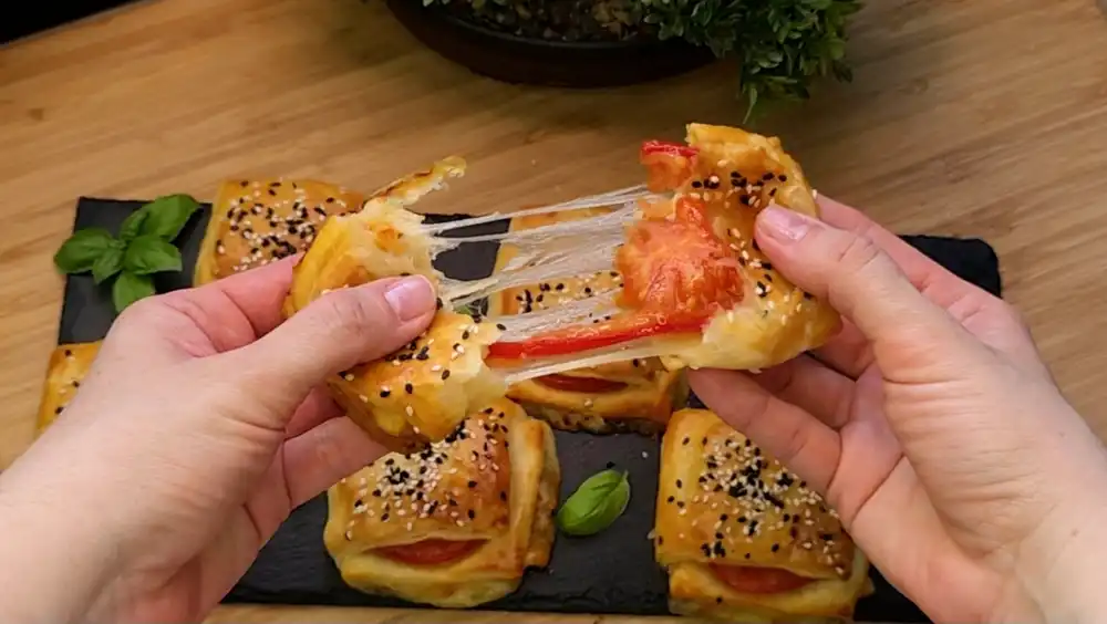 Detailansicht einer aufgeschnittenen Blätterteig-Tasche, die das rote Pesto, den saftigen Schinken und den Fäden ziehenden Mozzarella perfekt zeigt.