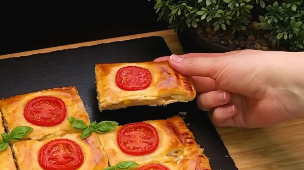 Detailansicht einer aufgeschnittenen Blätterteig-Tasche, die die saftige Füllung aus Thunfisch, Mais, Mayonnaise und Fäden ziehendem Käse zeigt.