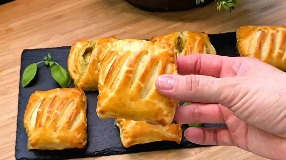 Detailansicht eines angebissenen Blätterteig-Muffins, die den cremigen Vanillepudding, die fruchtige Brombeere und die gerösteten Mandeln auf der krossen Kruste zeigt.