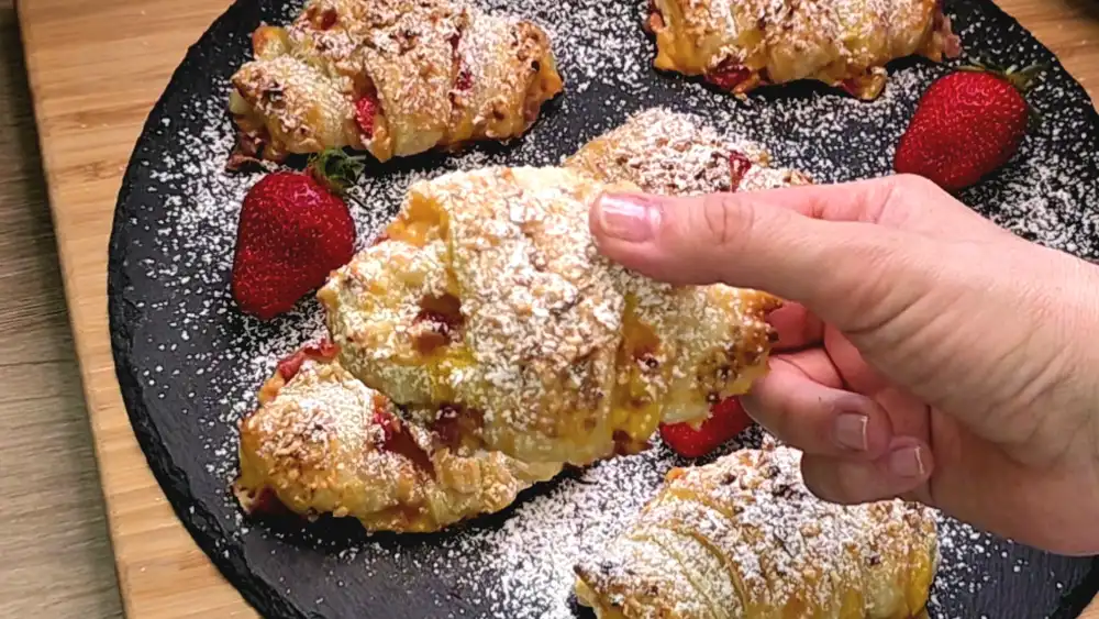 Detailansicht eines frisch gebackenen Croissants mit sichtbarer Puddingfüllung und Haselnusskruste.