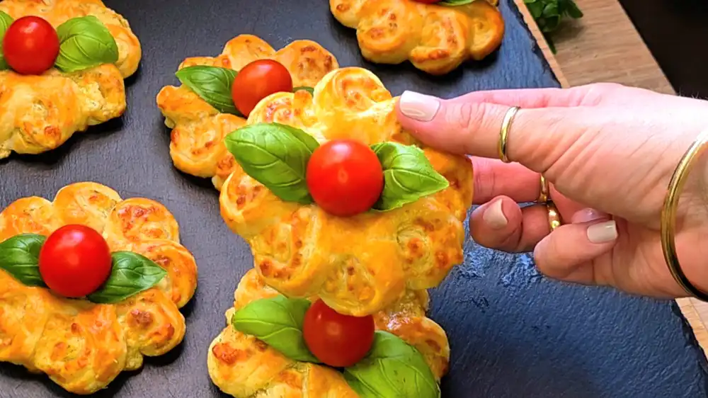 Detailansicht einer gebackenen Blätterteig-Käseblume, bei der die einzelnen Blätterteig-Schichten und der Kräuterfrischkäse sichtbar sind.