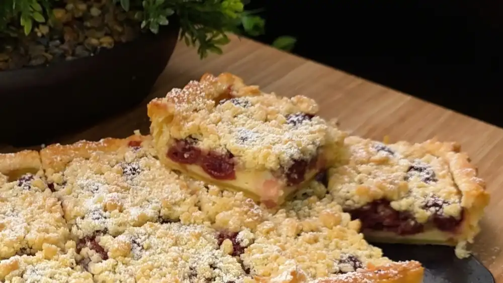 Detailansicht eines Kuchenschnitts mit saftigen Kirschen, cremiger Quarkschicht und dicken Streuseln.