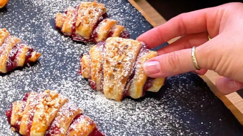 Detailansicht eines frisch aufgeschnittenen Marmeladen-Croissants mit sichtbarer fruchtiger Füllung.