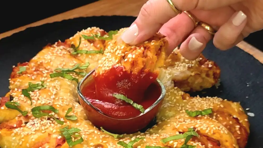 Detailansicht eines aufgeschnittenen Pizzakranz-Segments mit geschmolzenem Käse und frischem Basilikum.