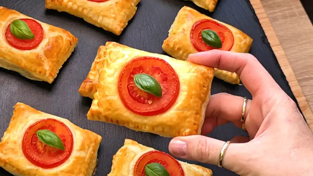 Detailansicht einer halbierten Blätterteig-Tasche mit heraustretendem, geschmolzenem Käse, feinem Schinken und cremiger Frischkäseschicht.