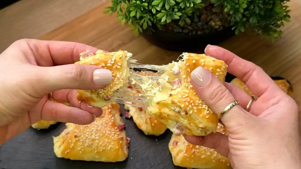 Detailansicht eines frisch gebackenen Schinken-Käse-Dreiecks mit sichtbarem geschmolzenem Käse und Schinkenstreifen.