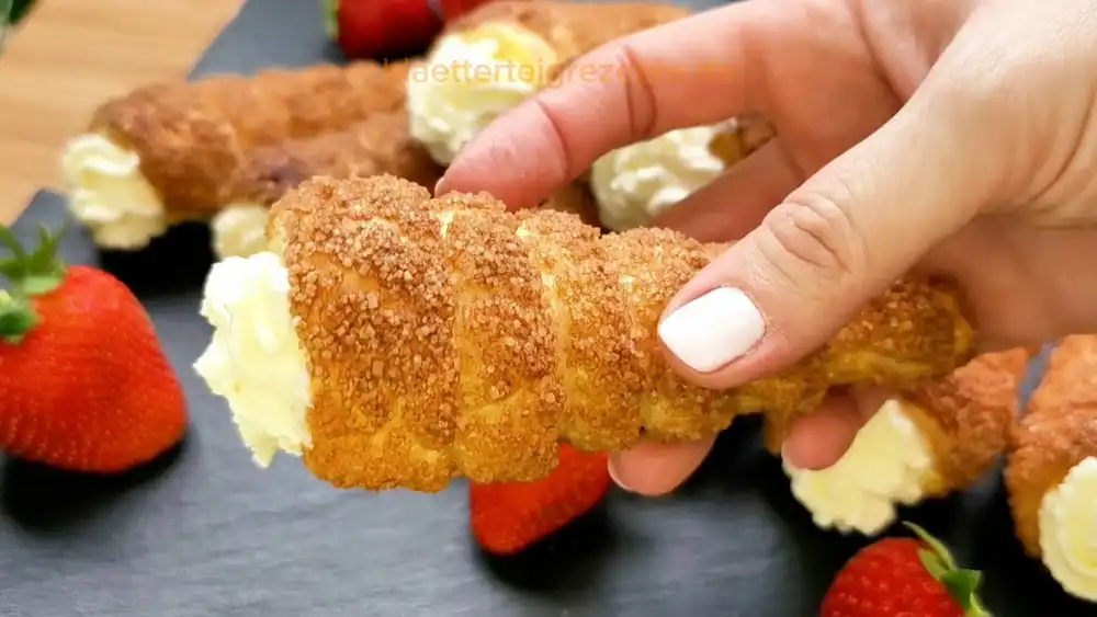 Detailansicht einer frisch gebackenen Vanille-Rolle, bei der die knusprige Zimt-Zucker-Schicht und die luftige Vanille-Sahne-Creme im Fokus stehen.