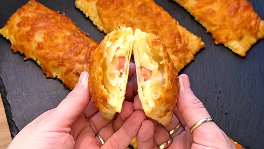 Detailansicht einer aufgeschnittenen Würstchen-Käse-Stange, bei der die cremige Kräuterfrischkäse-Schicht, die feinen Würstchenscheiben und der geschmolzene Käse im Inneren perfekt zu sehen sind.