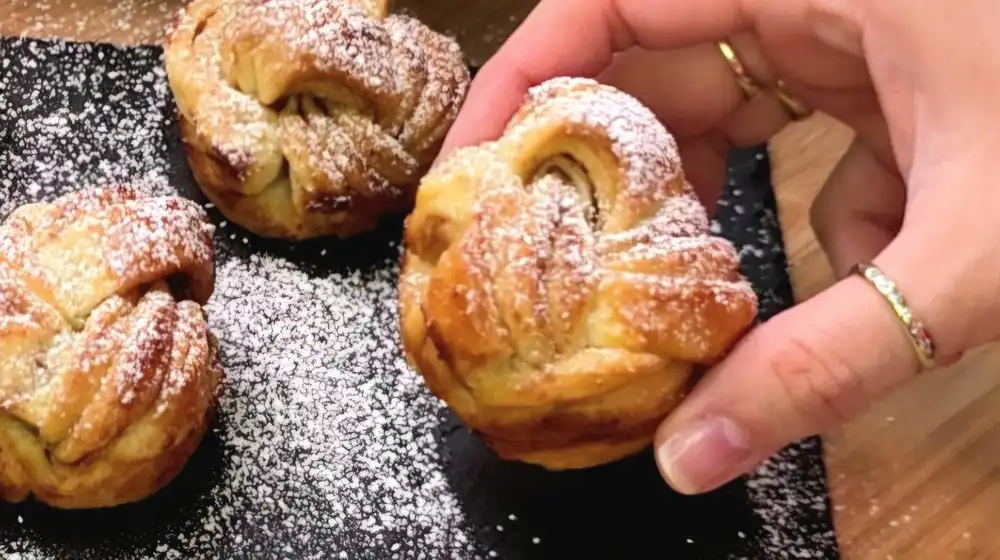 Detailansicht eines fluffigen Zimtknotens aus Blätterteig mit feinen Schichten und Zimt-Zucker-Füllung.