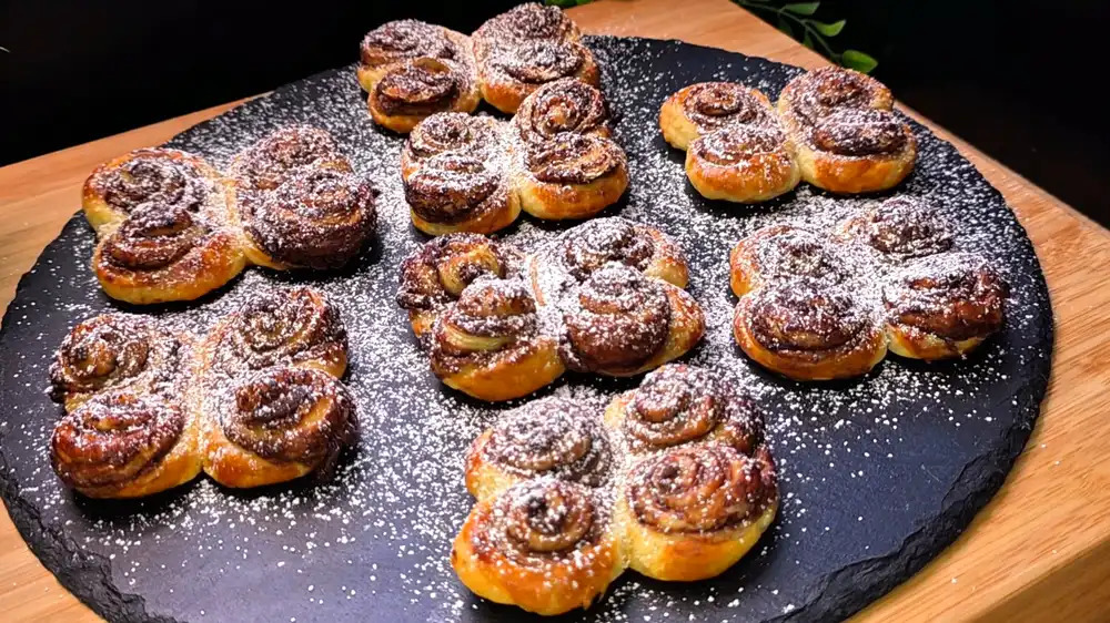 Goldbraun gebackene Blätterteig-Schmetterlinge mit feinen Nutella-Schichten in den Windungen, elegant bestäubt mit Puderzucker.