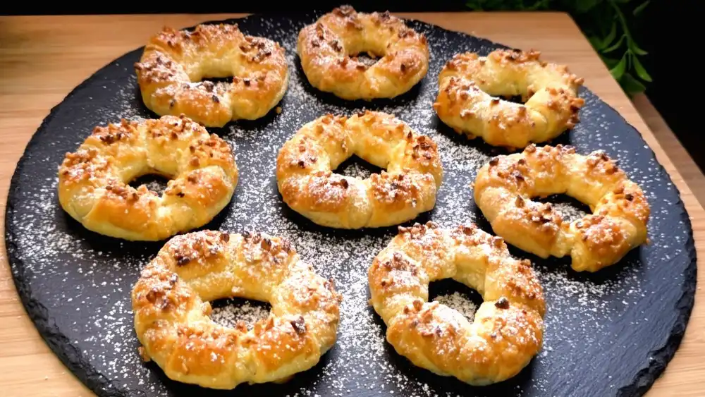 Goldbraun gebackene Blätterteig-Nutella-Ringe mit Haselnüssen und Puderzucker.