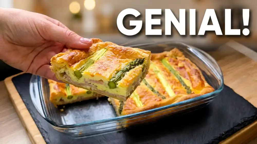 Ein goldbraun gebackener Blätterteig-Spargelkuchen mit Sauce Hollandaise und Schinken in einer Auflaufform.