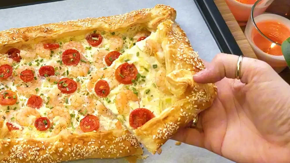 Detailansicht einer frisch gebackenen Seafood-Galette mit Fokus auf die saftigen, perfekt gegarten Garnelen, die geschmolzene Creme und den krossen Sesam-Teigrand.