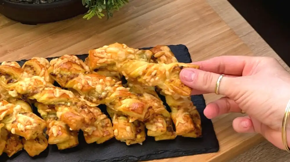 Detailansicht einer gedrehten Pesto-Stange mit Fokus auf die grünen Basilikumschichten und den kross gratinierten Käse in den Zwischenräumen.